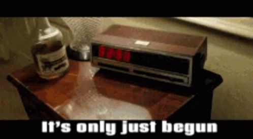 A Bottle Of Whiskey Sits Next To An Alarm Clock That Reads 8:08 GIF