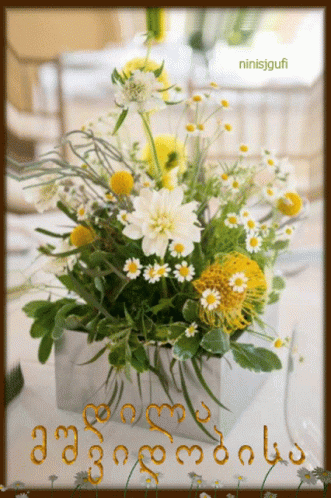A Bouquet Of Yellow And White Daisies In A Silver Vase With The Name Ninisjgufi On The Bottom GIF