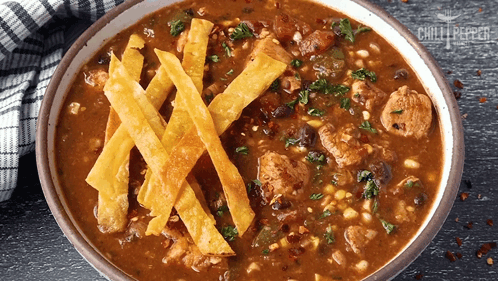 A Bowl Of Chili With Tortilla Strips On Top Of It GIF