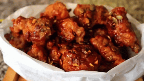 A Bowl Of Fried Chicken Covered In Sauce GIF
