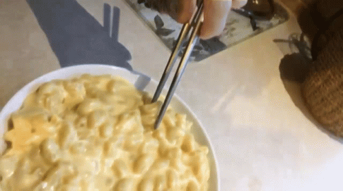 A Bowl Of Macaroni And Cheese Is Being Served With Chopsticks GIF