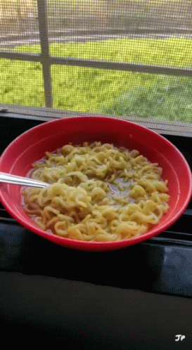 a bowl of noodles sits on a window sill with jp written on the bottom