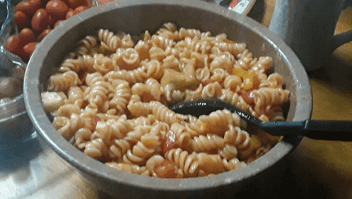 A Bowl Of Pasta With Tomatoes And A Spoon In It GIF