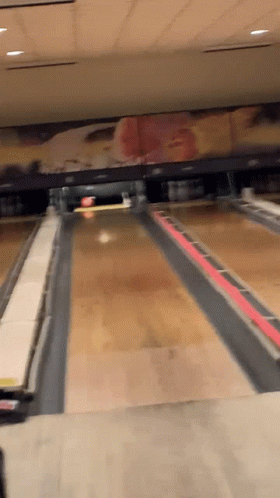 A Bowling Alley With A Painting Of A Cowboy On The Wall GIF