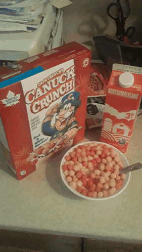 a box of canuck crunch cereal next to a bowl of cereal and a carton of milk