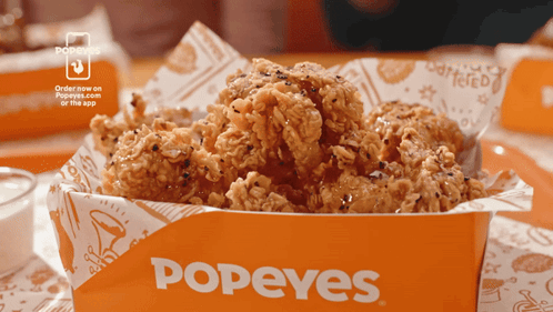 A Box Of Fried Chicken From Popeyes Is On A Table GIF