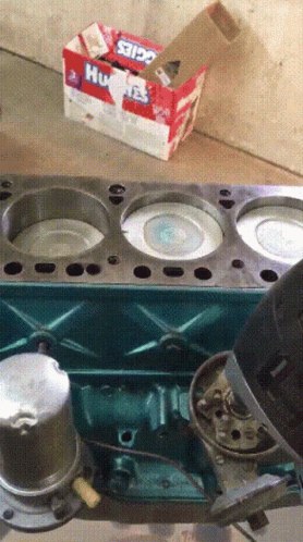 A Box Of Huskies Toothpaste Sits On The Floor Next To A Cylinder Head GIF