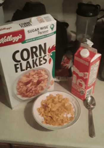 a box of kellogg 's corn flakes next to a plate of corn flakes