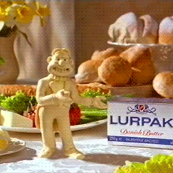 A Box Of Lurpak Butter Sits Next To A Figurine Of A Man GIF
