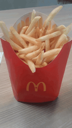 a box of mcdonald 's french fries sits on a wooden table