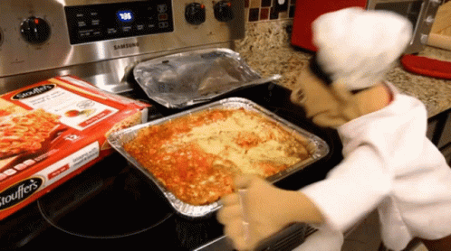 A Box Of Spaghettios Sits On A Stove Next To A Tray Of Lasagna GIF