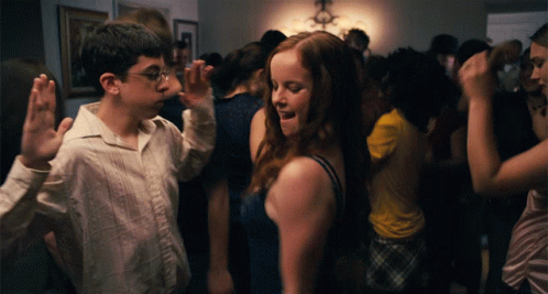 A Boy And A Girl Are Dancing In A Room Full Of People GIF