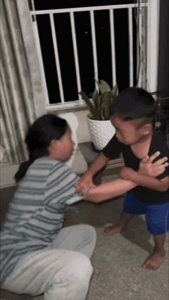 A Boy And A Girl Are Fighting In A Living Room With A Potted Plant In The Background . GIF