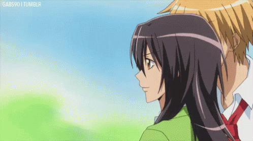 A Boy And A Girl Are Looking At Each Other And The Girl Is Wearing A Green Jacket . GIF