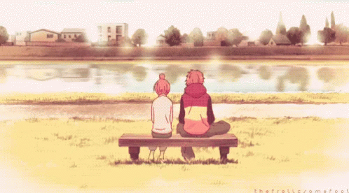 A Boy And A Girl Are Sitting On A Bench Looking At A Body Of Water GIF