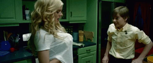 A Boy And A Girl Are Standing In A Kitchen With Green Cabinets GIF