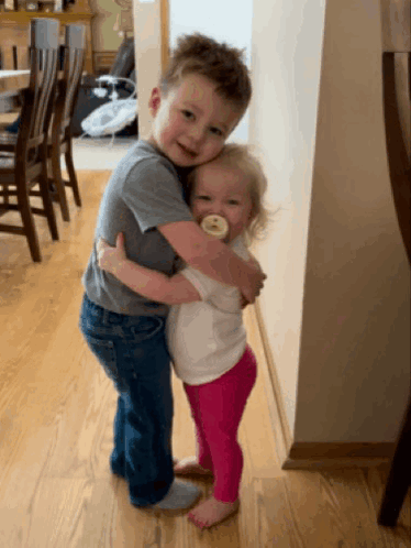 a boy and a girl hugging each other in a room