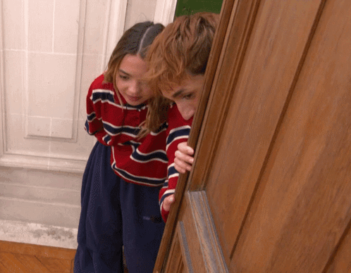 Boy And Girl Peeking Out Of Door GIF