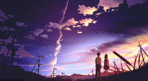 A Boy And A Girl Standing In Front Of A Sunset GIF