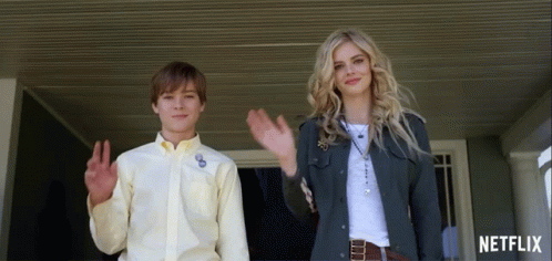 A Boy And A Woman Are Waving In Front Of A Netflix Ad GIF