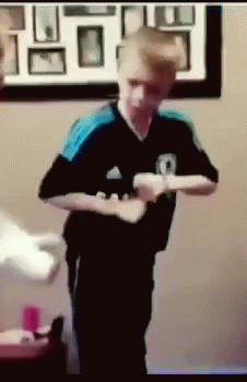 a boy in a black and blue adidas shirt is holding a wii controller