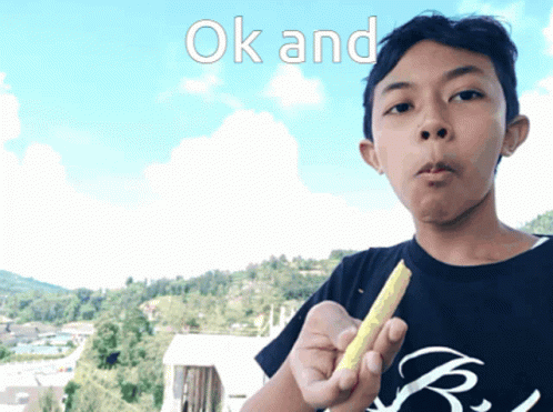 A Boy In A Black Shirt Is Holding A Yellow Object In His Hand With The Words Ok And Above Him GIF