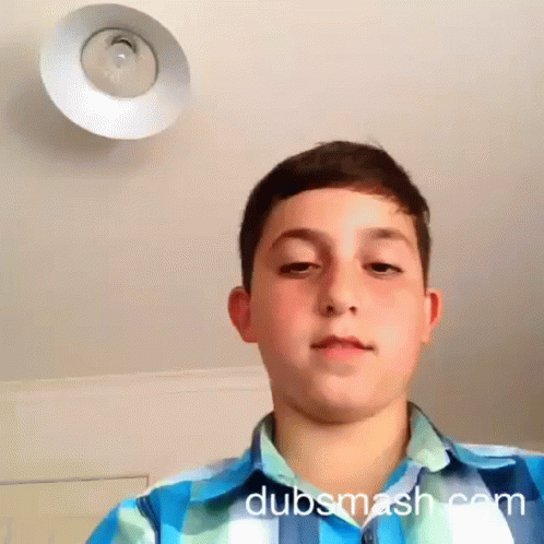 A Boy In A Blue And White Plaid Shirt Looks At The Camera With Dubsmash.com Written On The Bottom Right GIF
