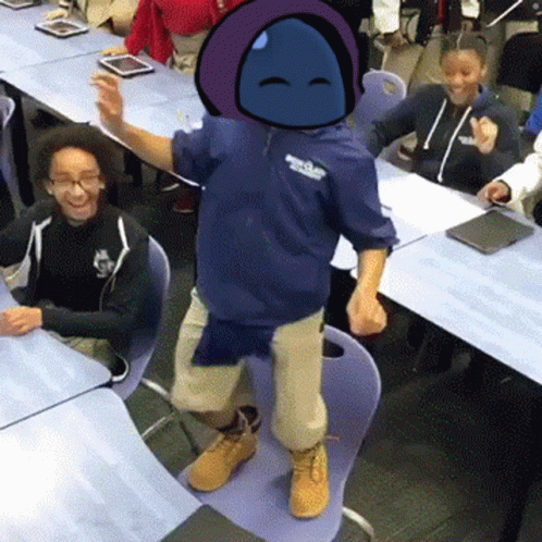 A Boy In A Blue Hoodie Is Standing On A Chair In Front Of A Group Of Children In A Classroom . GIF