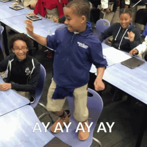 A Boy In A Blue Jacket Is Dancing In A Classroom With The Words " Ayay Ay Ay " On The Bottom GIF