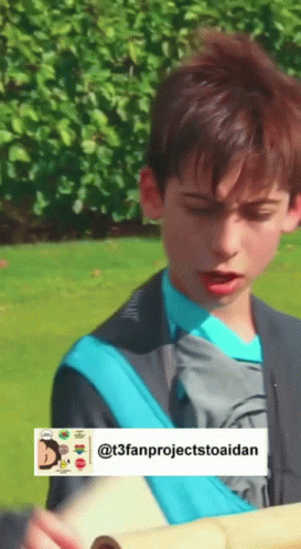 A Boy In A Blue Shirt Is Holding A Piece Of Paper In His Hand . GIF
