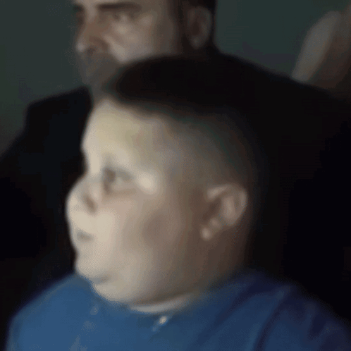A Boy In A Blue Shirt Is Sitting In Front Of A Man In A Suit GIF
