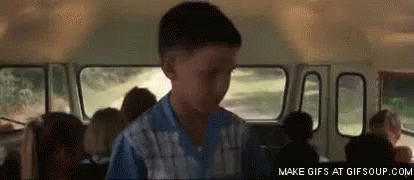 A Boy In A Blue Shirt Is Standing In A School Bus With Other Children . GIF