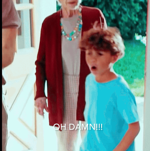 A Boy In A Blue Shirt Is Standing In Front Of An Older Woman And Says Oh Damn GIF