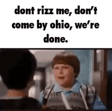 A Boy In A Blue Shirt Is Talking To Another Boy In A School Hallway . GIF