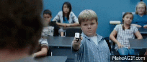 A Boy In A Classroom Is Pointing A Gun At Someone GIF