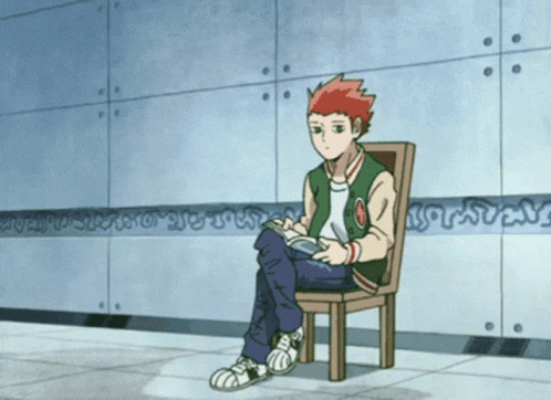 A Boy In A Green Jacket Sits In A Chair With His Legs Crossed While Reading A Book GIF