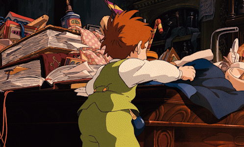 A Boy In A Green Vest Is Standing In Front Of A Pile Of Books And A Box That Says ' Gin ' On It GIF