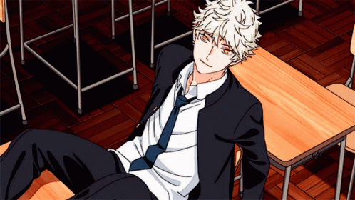 A Boy In A Suit And Tie Is Laying On A Desk GIF