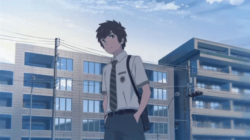 A Boy In A White Shirt And Tie Stands In Front Of Buildings GIF