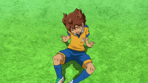 a boy in a yellow shirt and blue shorts is laying on the grass with his hands reaching out towards him