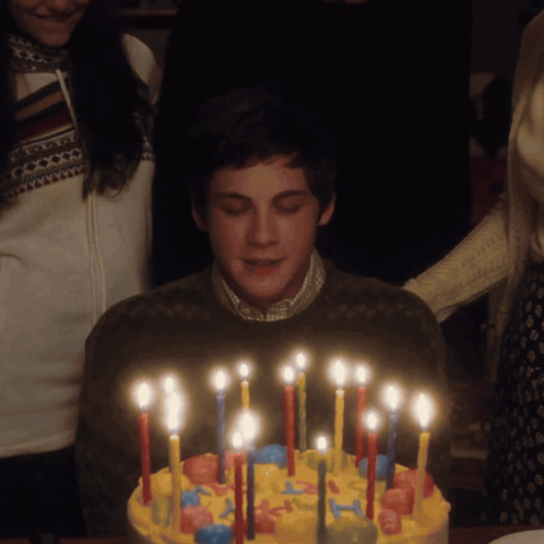 A Boy Is Blowing Out Candles On A Cake GIF