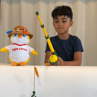 A Boy Is Holding A Fishing Rod Next To A Stuffed Penguin That Says Vote 4 Puget GIF