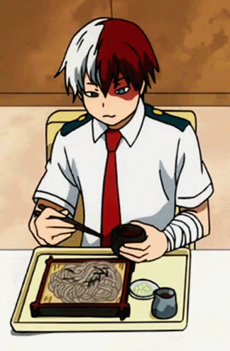 A Boy Is Sitting At A Table Eating Noodles With Chopsticks . GIF