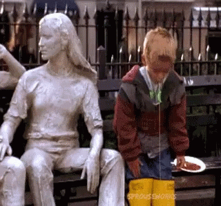 A Boy Is Sitting On A Bench Next To A Statue Of A Woman With Sprouts Enworks Written On The Bottom GIF