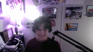 a boy is smiling in front of a microphone in a room with posters on the wall including one for star wars