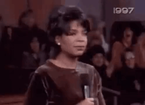 A Boy Is Standing In Front Of A Crowd With His Mouth Open . GIF