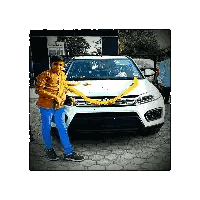 a boy is standing in front of a white car with a yellow ribbon around it