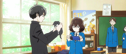 A Boy Is Taking A Picture Of A Girl In A Classroom With A Sign That Says Step In The Background . GIF