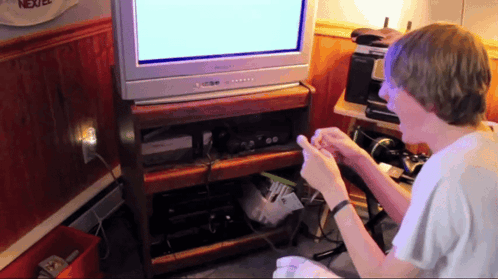 A Boy Playing A Video Game In Front Of A Tv That Says Nextel On It GIF