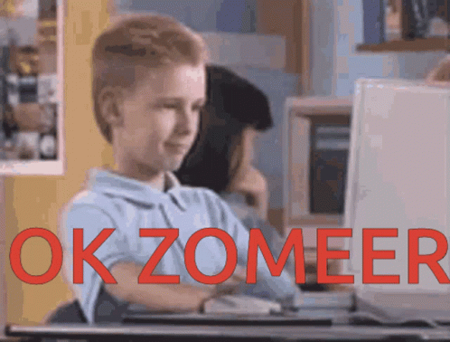 A Boy Sitting In Front Of A Computer With The Words Okzomeer Written In Red GIF